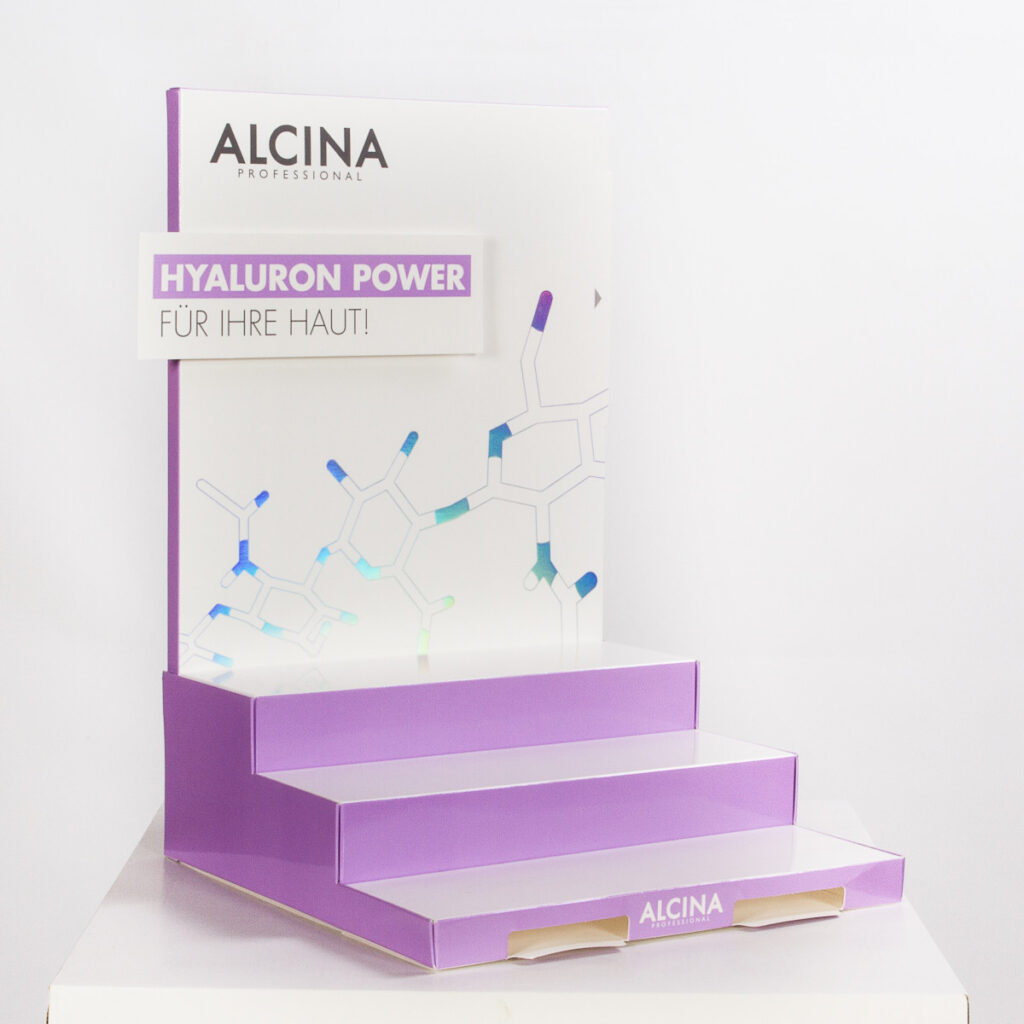 Beispiel für ein Thekendisplay. Das Display ist treppenförmig und hat eine mit Produktnamen und Claim bedruckte Rückwand