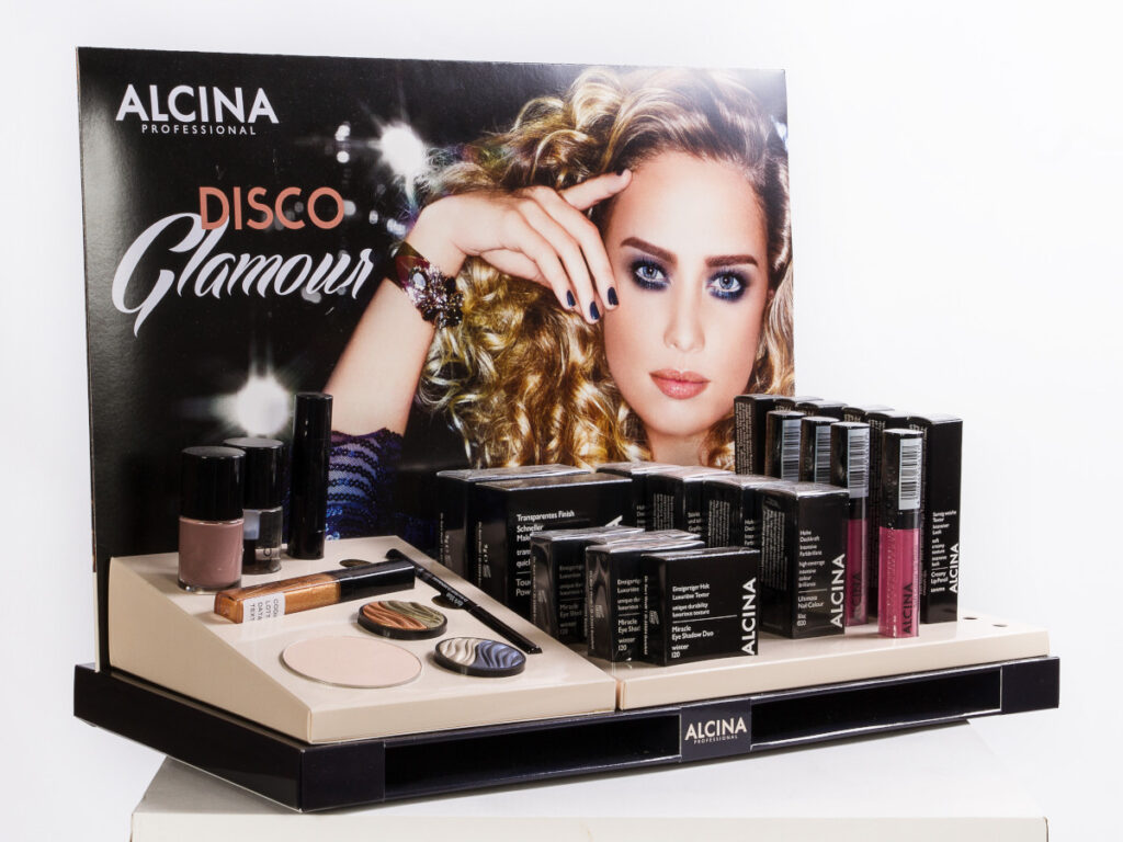 Beispiel für ein Thekendisplay für Kosmetikprodukte. Verschiedene Produkte sind in passenden Aussparungen vor einer bedruckten Rückwand angeordnet.