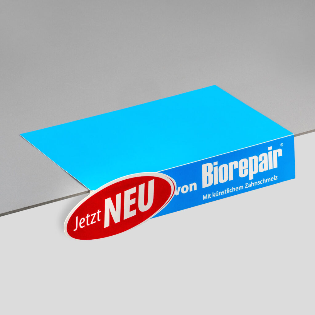 Beispiel für eine Regalschiene zur Dekoration. Die Vorderseite ist mit dem Produktnamen und dem Zusatz "Jetzt NEU" beschriftet.