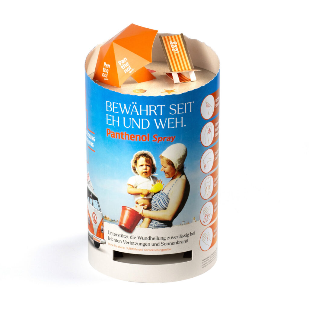 Beispiel für ein Thekendisplay in Dosenform. Auf der Oberseite sind ein Sonnenschirm und ein Liegestuhl nachgebildet. An der Seite ist ein Schlitz zur Entnahme des Produkts.